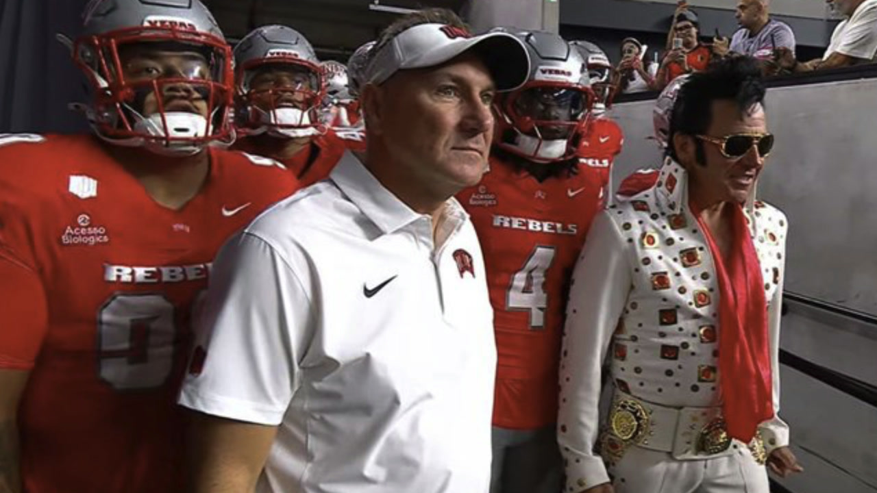 Dan Mullen leading UNLV onto the field alongside an Elvis impersonator