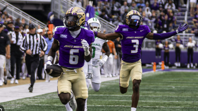 Two James Madison players celebrate down the sideline against Marshall