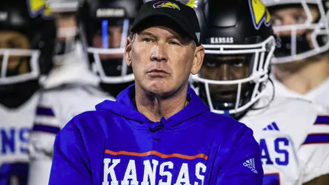 Lance Leipold in a Kansas hoodie with his players lined up behind him